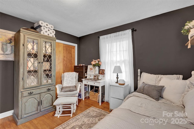 bedroom with hardwood / wood-style floors and a textured ceiling