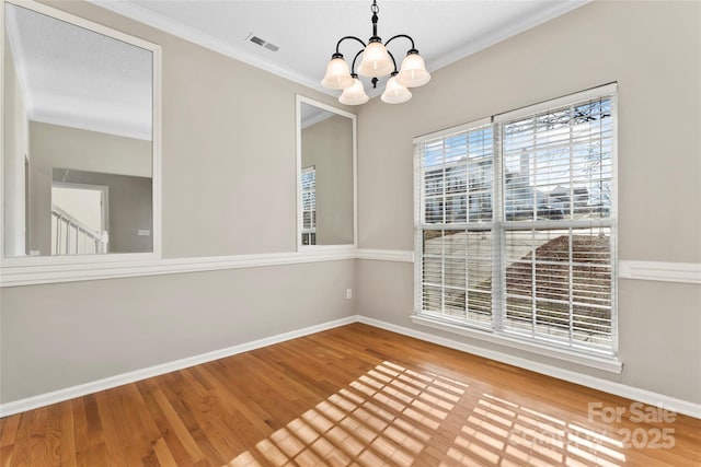 spare room with crown molding, wood-type flooring, and an inviting chandelier