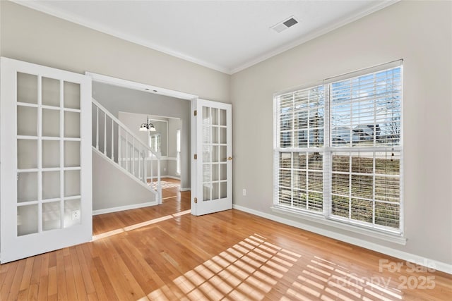 empty room featuring ornamental molding, french doors, a chandelier, and wood-type flooring