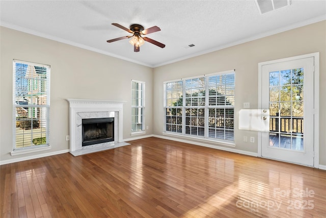 unfurnished living room with a high end fireplace, ornamental molding, a textured ceiling, ceiling fan, and hardwood / wood-style flooring