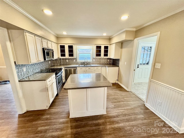 kitchen featuring sink, a center island, decorative backsplash, white cabinets, and appliances with stainless steel finishes