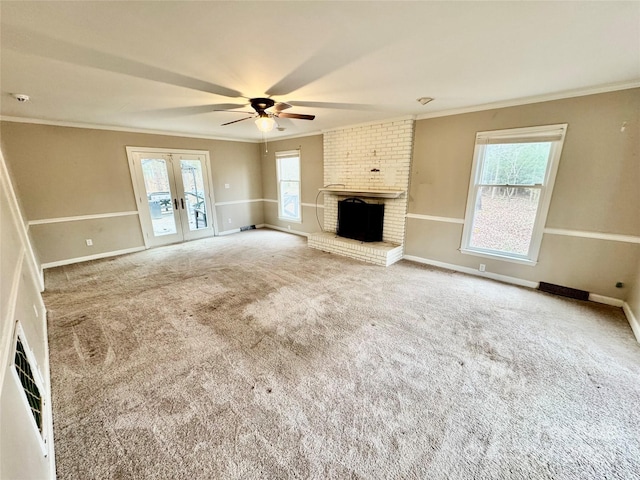 unfurnished living room with carpet flooring, french doors, ornamental molding, ceiling fan, and a fireplace