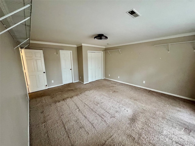 unfurnished bedroom featuring carpet floors, two closets, and ornamental molding