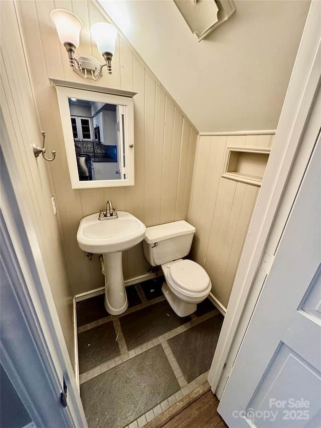 bathroom featuring wood walls, tile patterned flooring, and toilet