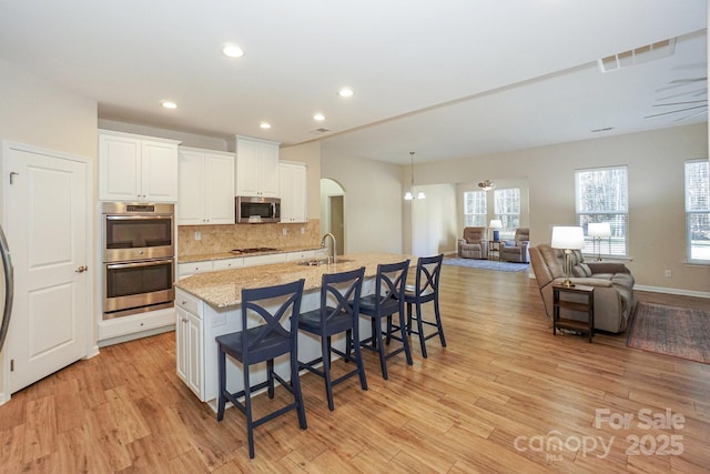 kitchen with white cabinets, a kitchen island with sink, a breakfast bar area, and stainless steel appliances