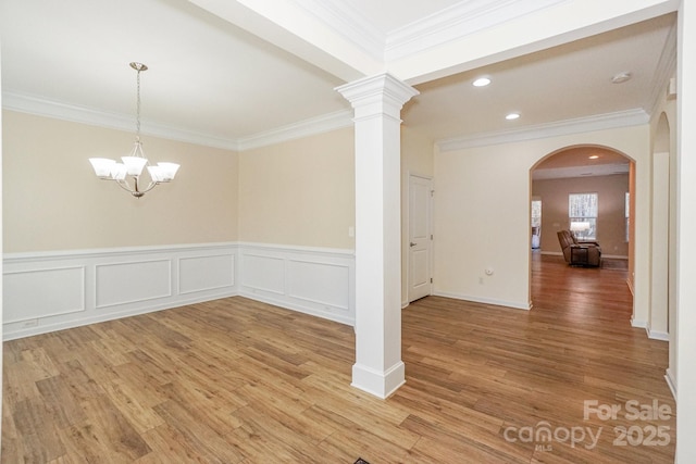 spare room featuring hardwood / wood-style flooring, crown molding, and an inviting chandelier