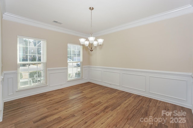 unfurnished dining area with wood-type flooring, crown molding, and a notable chandelier