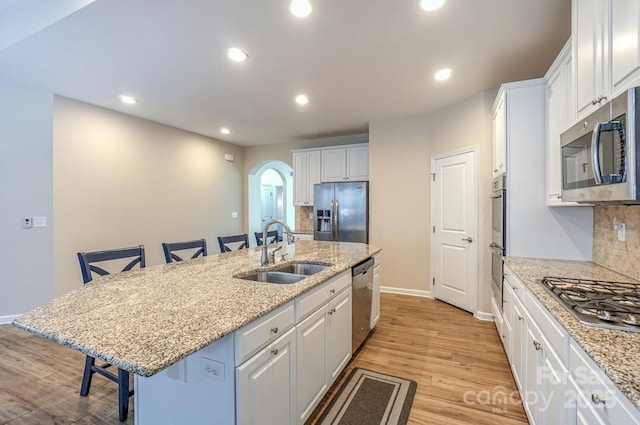 kitchen featuring sink, appliances with stainless steel finishes, a breakfast bar area, and an island with sink