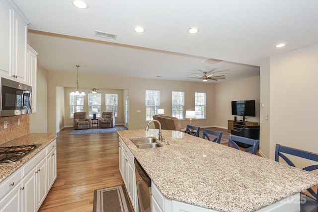 kitchen featuring white cabinets, stainless steel appliances, a kitchen bar, and a center island with sink