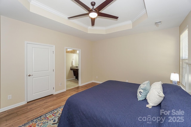 bedroom with wood-type flooring, ceiling fan, a raised ceiling, ensuite bath, and ornamental molding