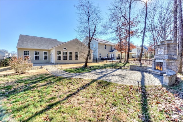 rear view of property featuring a patio area, a lawn, and an outdoor stone fireplace