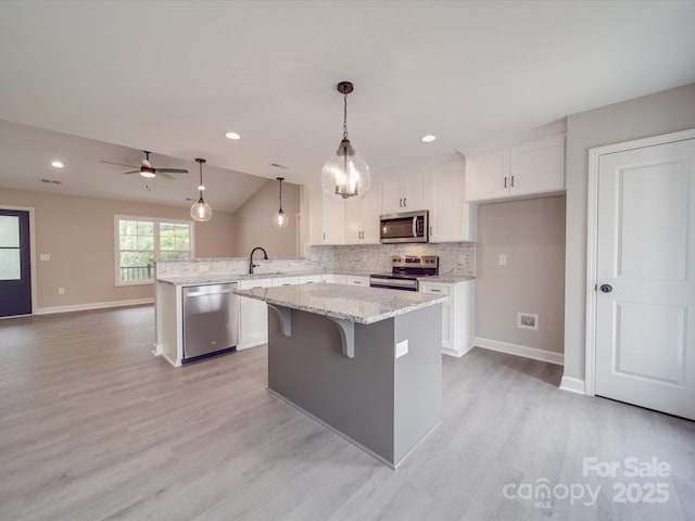 kitchen with a peninsula, white cabinetry, stainless steel appliances, and decorative backsplash