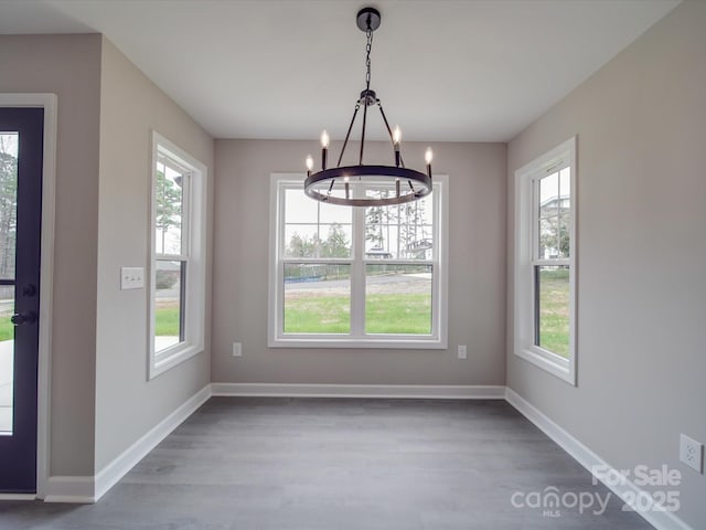 unfurnished dining area featuring a chandelier, wood finished floors, and baseboards