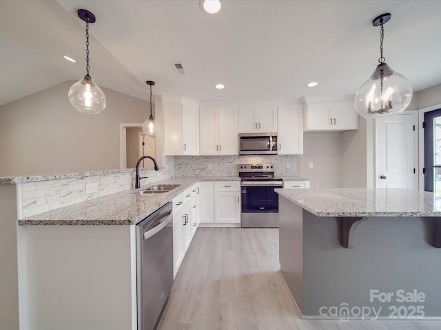 kitchen with a sink, visible vents, white cabinetry, appliances with stainless steel finishes, and backsplash