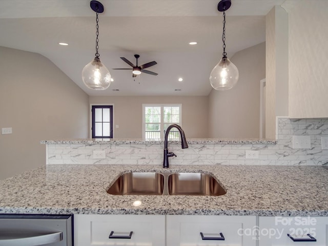 kitchen with lofted ceiling, decorative light fixtures, a sink, and light stone countertops