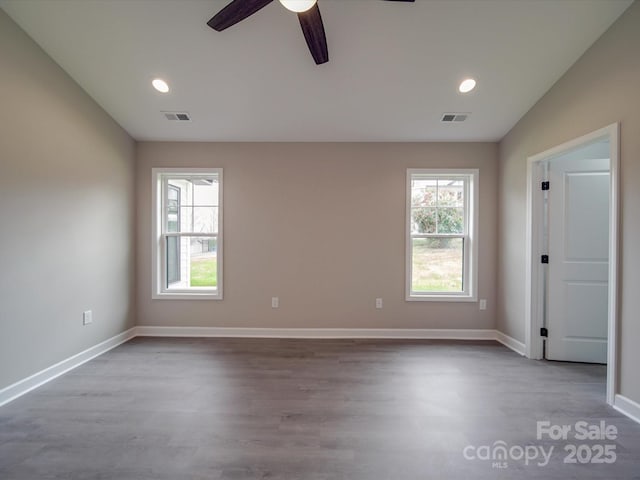 spare room with wood finished floors, visible vents, and baseboards