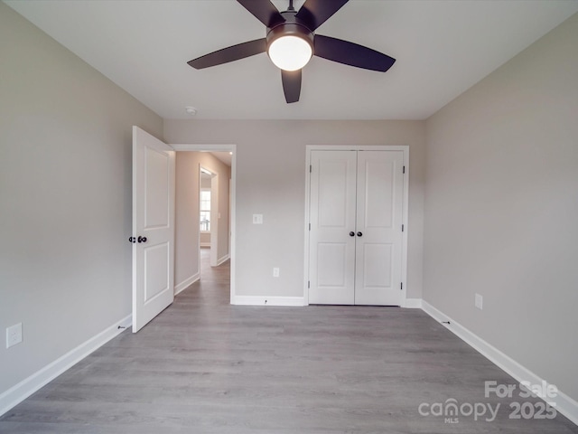 unfurnished bedroom with a ceiling fan, a closet, baseboards, and wood finished floors