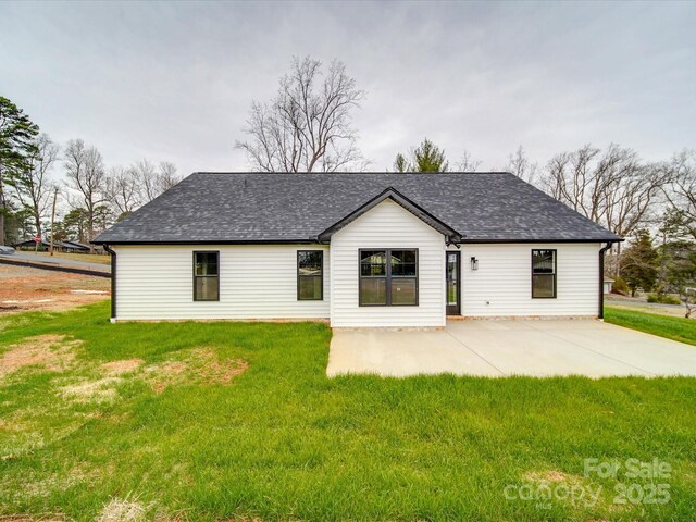 rear view of property with a patio area, a shingled roof, and a yard