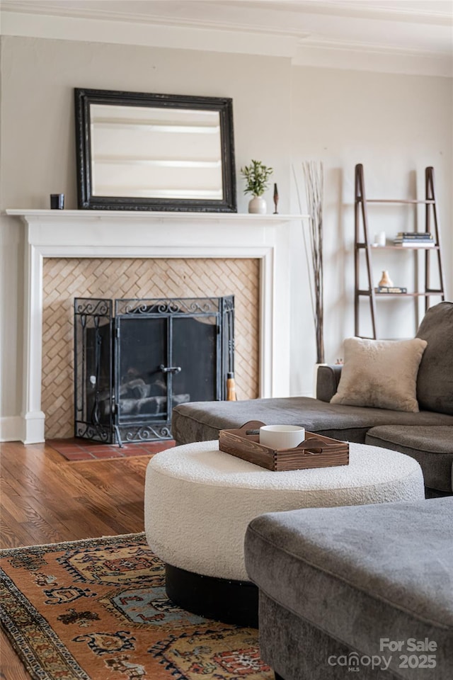 living room with a tile fireplace, hardwood / wood-style floors, and ornamental molding