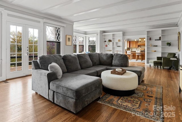 living room featuring beamed ceiling, french doors, and light wood-type flooring