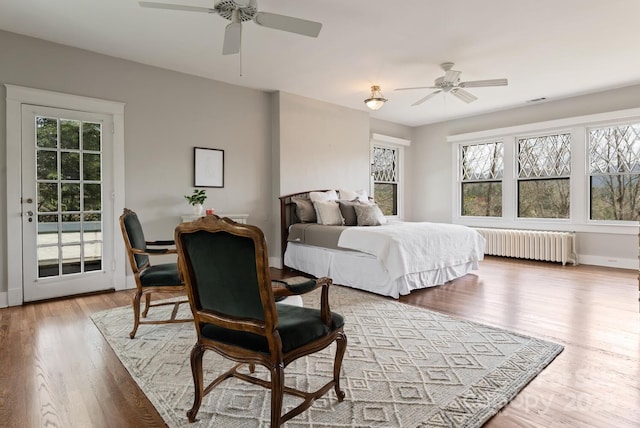 bedroom featuring radiator heating unit, hardwood / wood-style flooring, ceiling fan, and access to outside