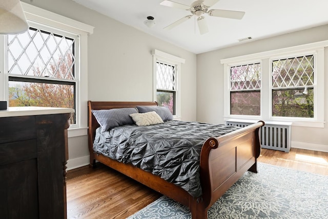 bedroom with hardwood / wood-style flooring, ceiling fan, and multiple windows