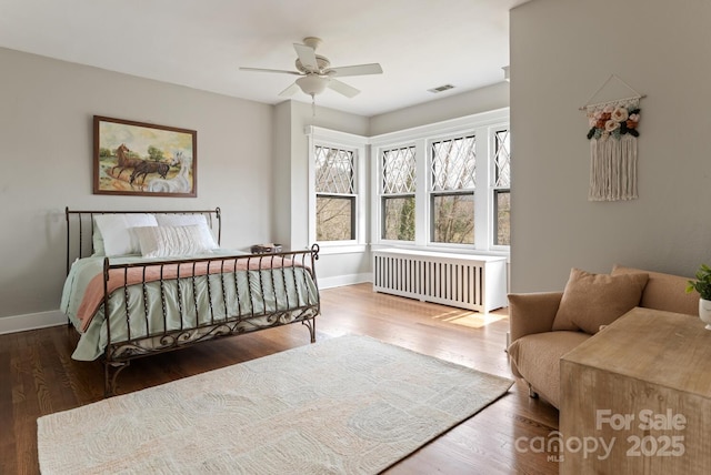 bedroom featuring dark hardwood / wood-style flooring, radiator, and ceiling fan