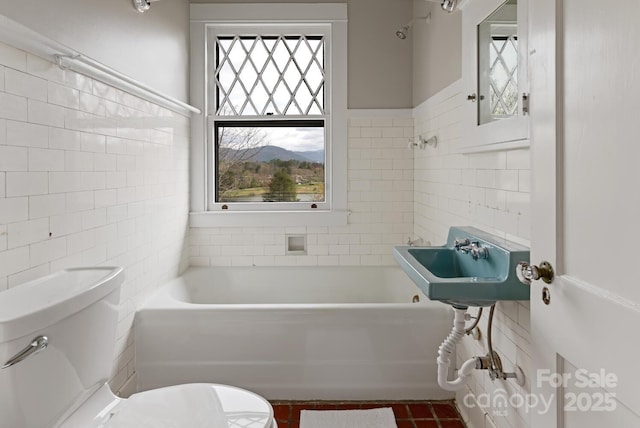 bathroom featuring toilet, tile walls, and a tub