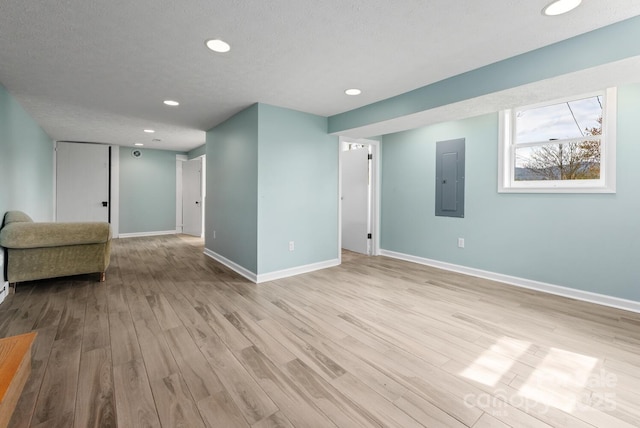 spare room featuring a textured ceiling, electric panel, and light hardwood / wood-style floors