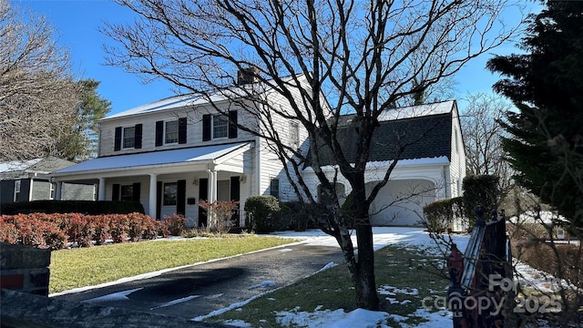 view of front of home featuring a garage, a front yard, and covered porch