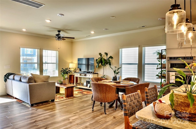 dining room featuring light wood-type flooring, ceiling fan, and ornamental molding