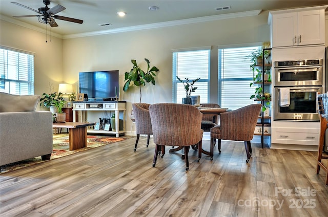 dining space with ornamental molding, ceiling fan, and light hardwood / wood-style floors