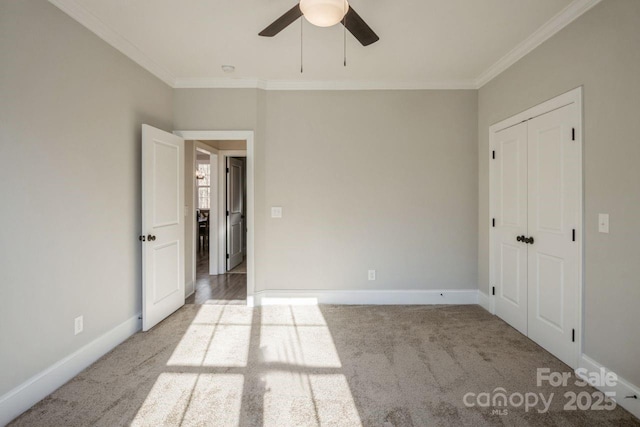 unfurnished bedroom featuring ceiling fan, light carpet, a closet, and ornamental molding