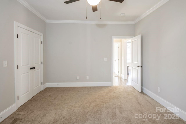 unfurnished bedroom featuring ceiling fan, light colored carpet, a closet, and crown molding