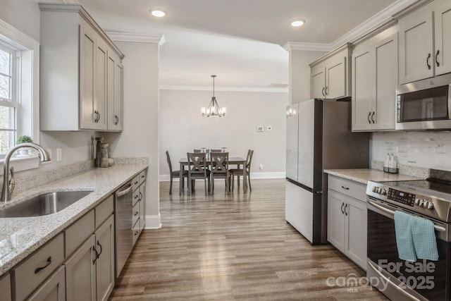 kitchen featuring appliances with stainless steel finishes, gray cabinetry, light stone countertops, pendant lighting, and sink