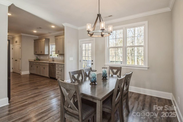 dining area featuring sink, dark hardwood / wood-style floors, ornamental molding, and an inviting chandelier