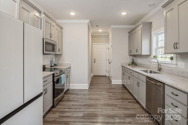 kitchen featuring appliances with stainless steel finishes, gray cabinetry, crown molding, light stone counters, and sink