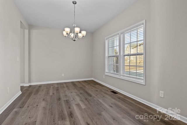 spare room with a chandelier and hardwood / wood-style flooring