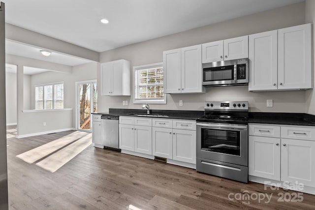 kitchen featuring a wealth of natural light, white cabinets, appliances with stainless steel finishes, dark hardwood / wood-style flooring, and sink