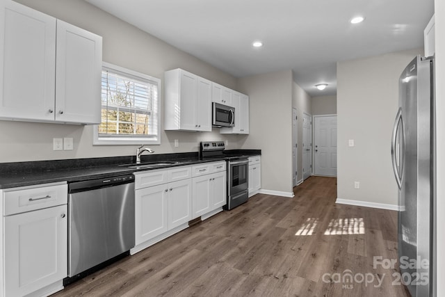 kitchen with dark hardwood / wood-style floors, stainless steel appliances, white cabinets, and sink