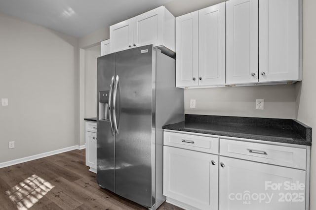 kitchen with stainless steel refrigerator with ice dispenser, dark wood-type flooring, and white cabinets