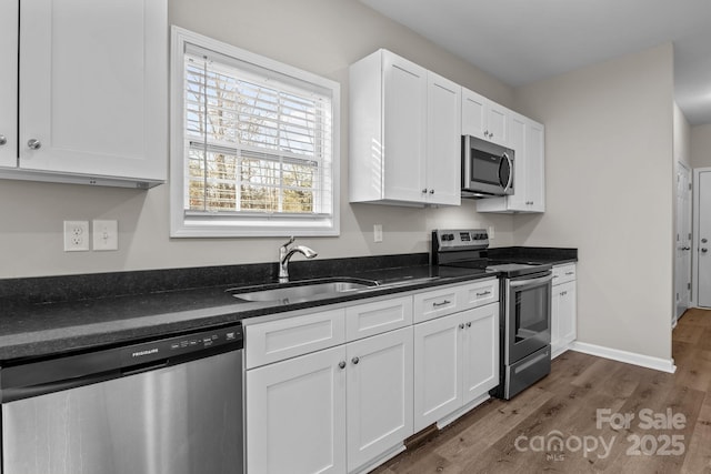 kitchen featuring dark wood-type flooring, white cabinets, appliances with stainless steel finishes, and sink