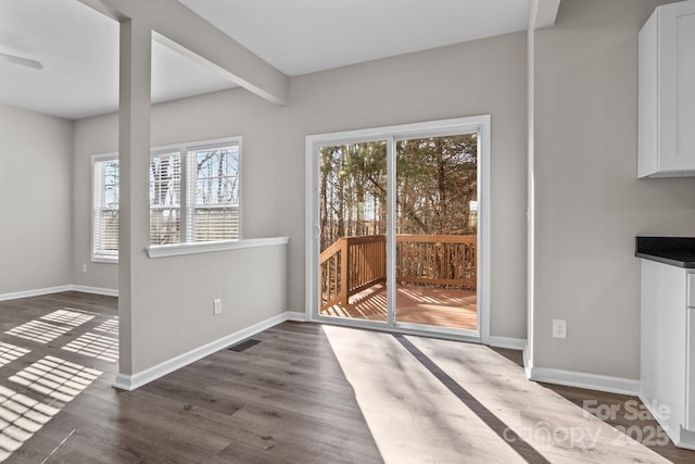 unfurnished dining area with beam ceiling and dark hardwood / wood-style floors