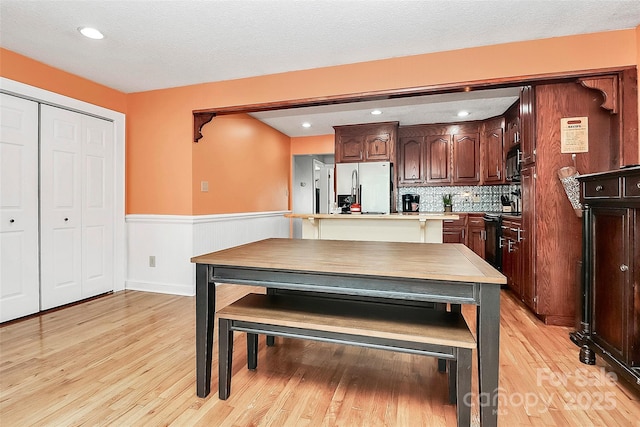 kitchen featuring backsplash, electric range, refrigerator, and light hardwood / wood-style floors