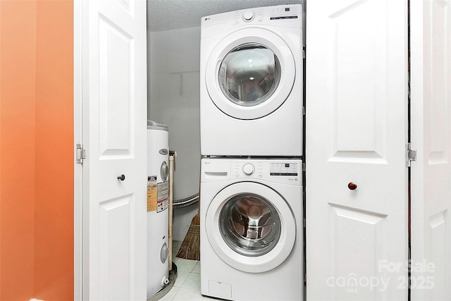 laundry room with stacked washing maching and dryer, electric water heater, light tile patterned floors, and a textured ceiling