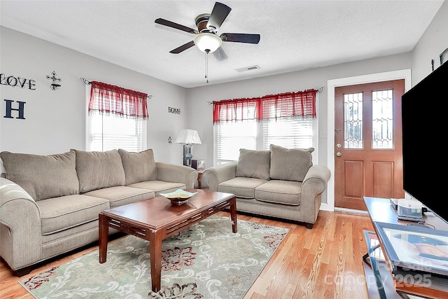 living room with ceiling fan, plenty of natural light, a textured ceiling, and light hardwood / wood-style flooring