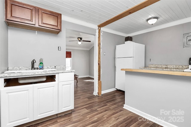 kitchen with dark wood-type flooring, white cabinetry, white refrigerator, ornamental molding, and ceiling fan