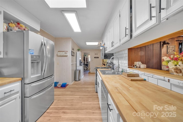 kitchen with white cabinetry, butcher block counters, stainless steel fridge with ice dispenser, and a skylight