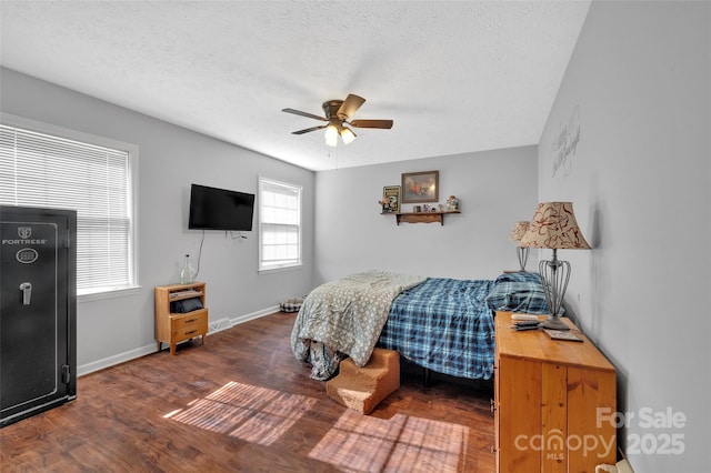 bedroom with multiple windows, a textured ceiling, dark hardwood / wood-style flooring, and ceiling fan