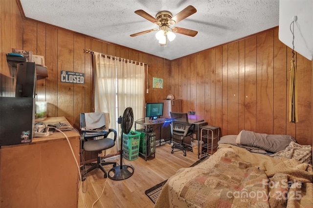 office space featuring ceiling fan, light hardwood / wood-style flooring, wood walls, and a textured ceiling